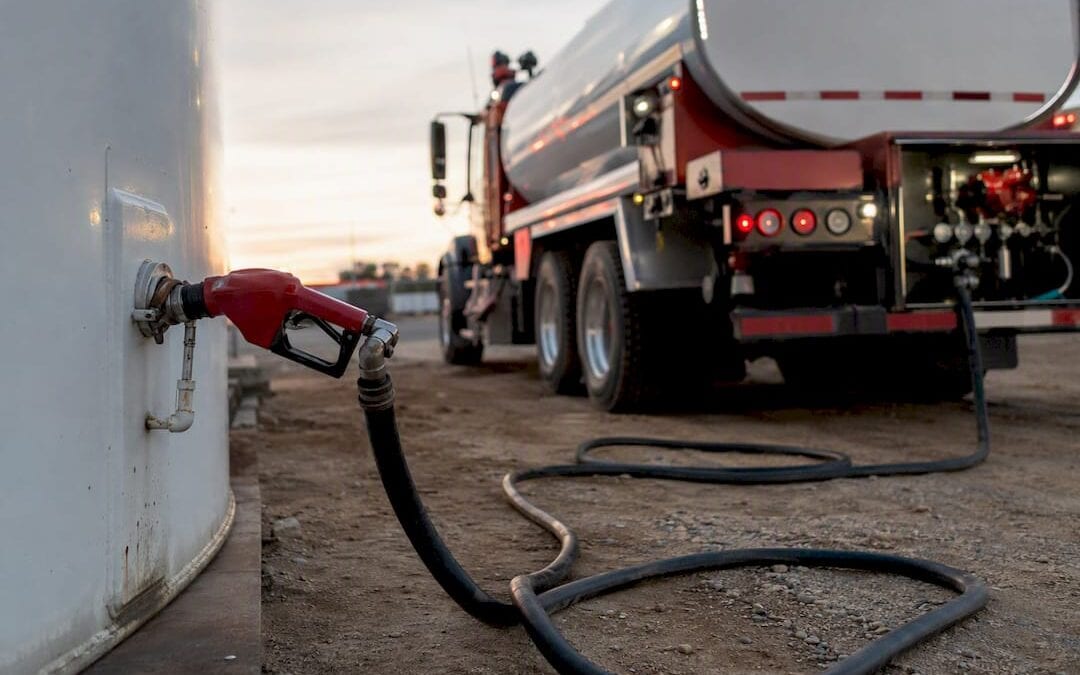 Unbranded fuel delivery truck and tanks in industrial yard