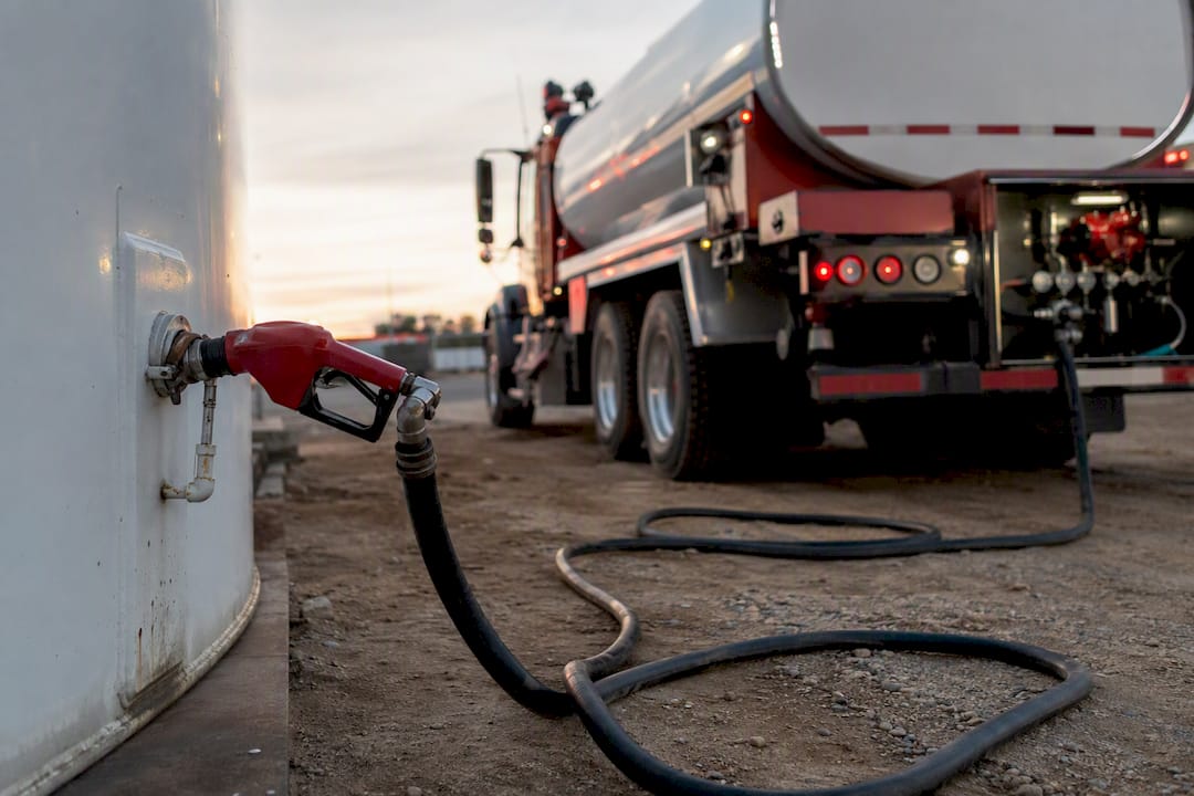 Unbranded fuel delivery truck and tanks in industrial yard