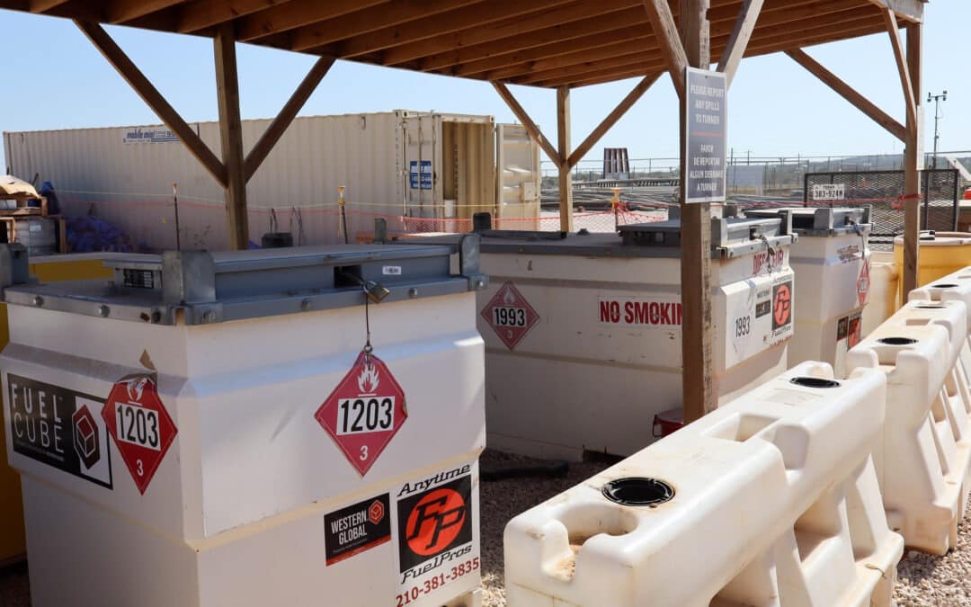 Fuel storage tanks with hazard labels and safety signs at fuel station.